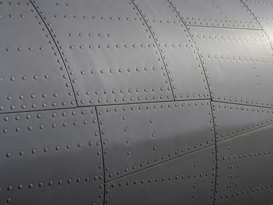 Close-up of flush rivets and overlapping panel boundaries on a metal aircraft fuselage